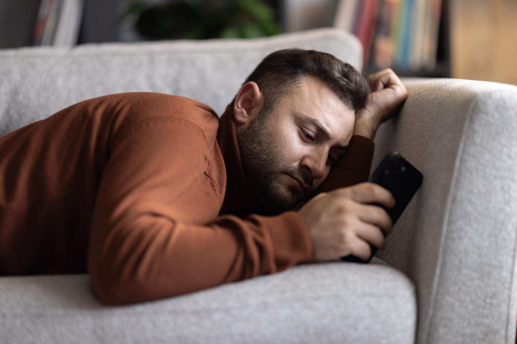 férfi kanapén fekve telefonozik