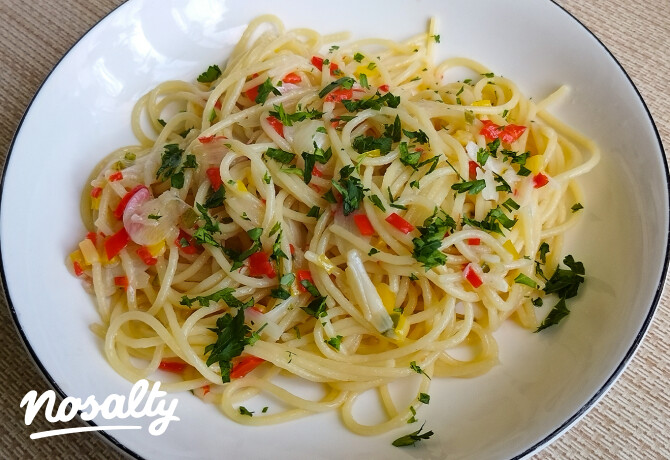 Fokhagymás-chilis spagetti fehér tányérban, friss petrezselyemmel, csilipaprikával és olívaolajjal tálalva.