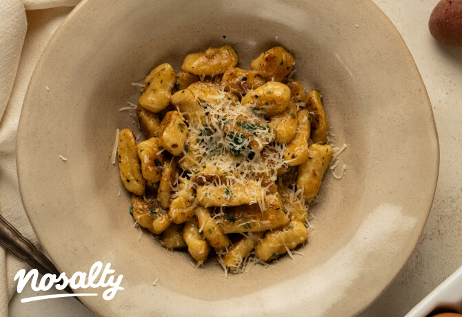 Vajon lepirított gnocchi fokhagymával és chilivel, felülről fotózva, mélytányérban, gazdagon megszórva sajttal