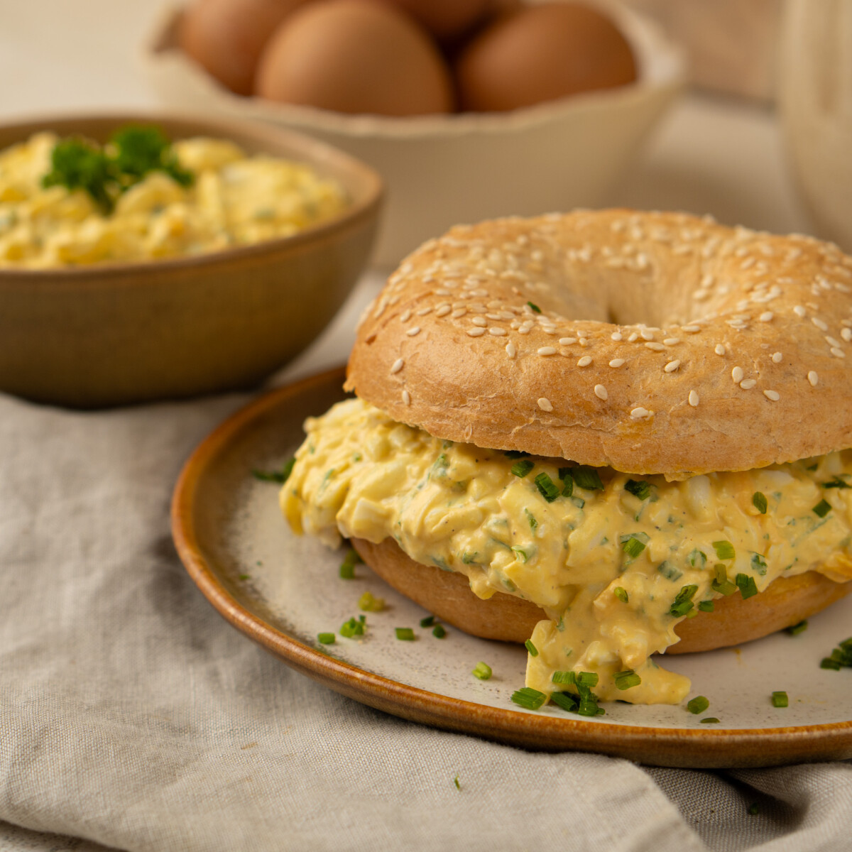 Szezámmagos bagel gazdagon megtöltve, szaftos, zöldfűszeres tojáskrémmel