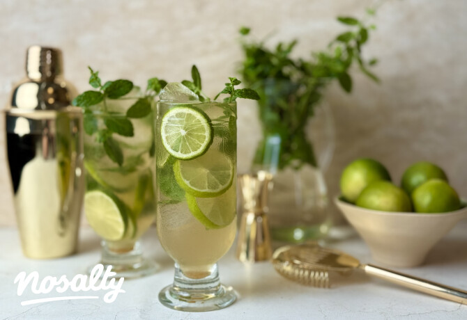 Mojito-koktél hosszú pohárban, lime szeletekkel, jégkockákkal és mentalevéllel,