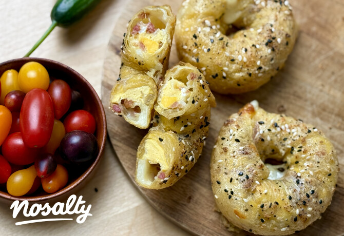 Bagel alakú, szezámmaggal megszórt rizslapos reggeli tojással, baconnel és sajttal, félbevágva, színes koktélparadicsomokkal tálalva.